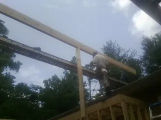 Carpenter setting a ridge beam over a new addition frame — Ice Dam Removal by Roofing Brothers in Mc Donough