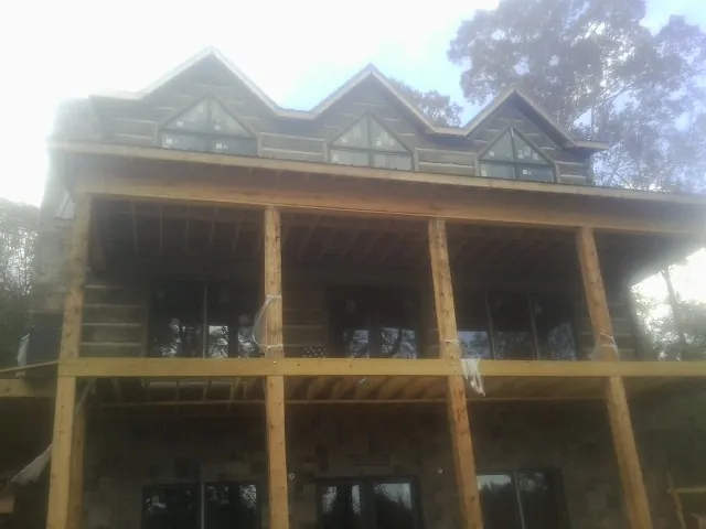 Dormers and porch framing on a large log home under construction — Roof Coating work by our crew in Mc Donough