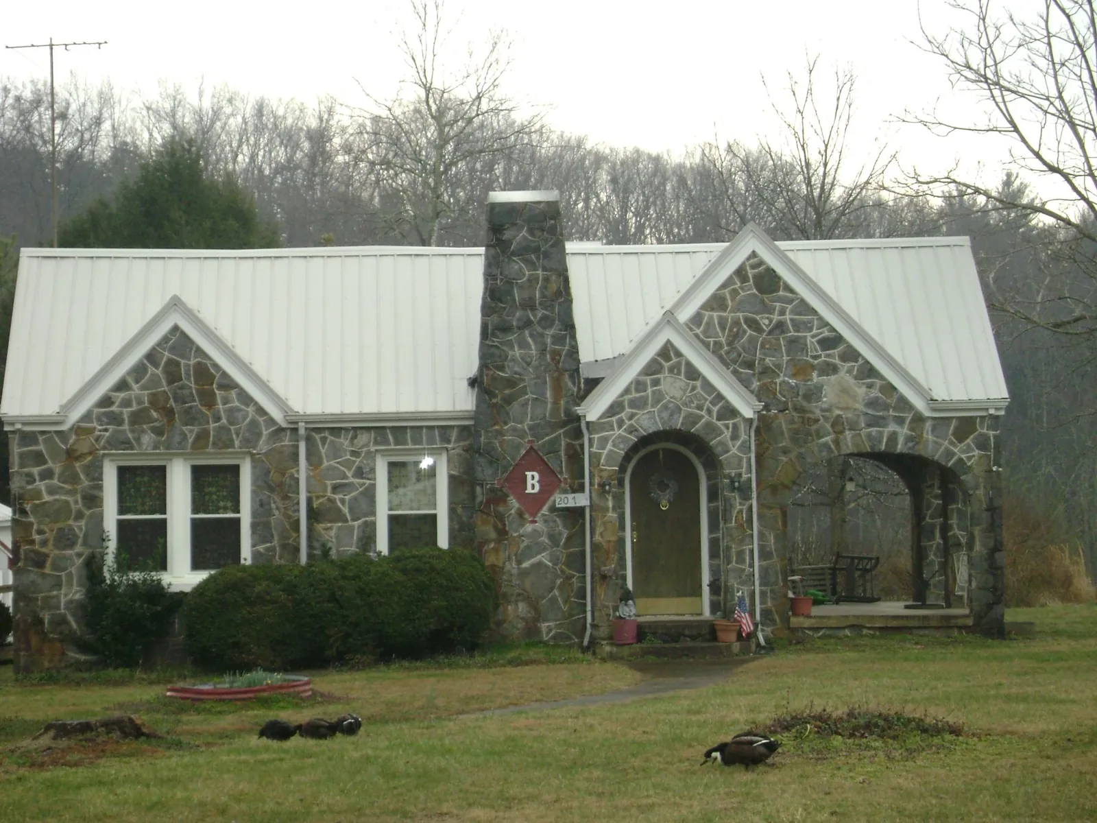 White metal roof on a stone cottage with steep gables in Mc Donough