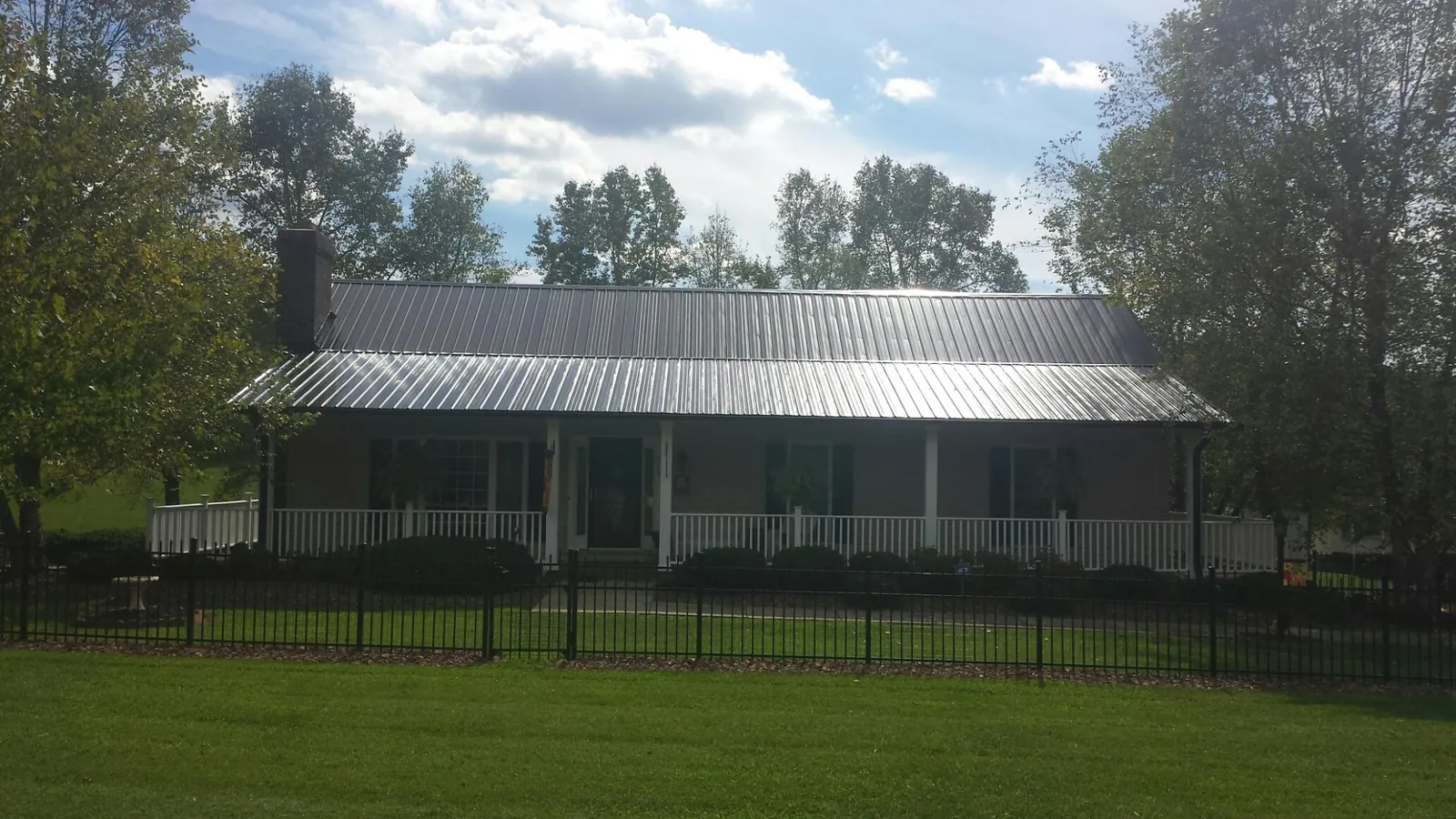 Gray metal roof on a brick ranch with a full width front porch — Gutter Guard Installation work by our crew in Mc Donough