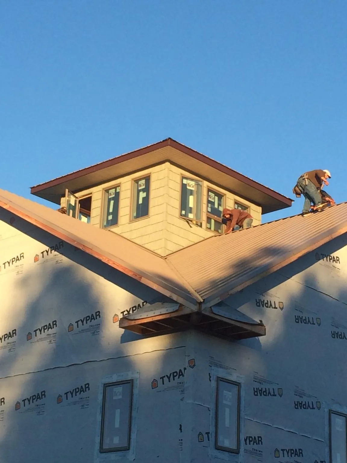 Roofers working around a rooftop cupola on a new metal roof at sunset — Roof Waterproofing in Mc Donough by Roofing Brothers